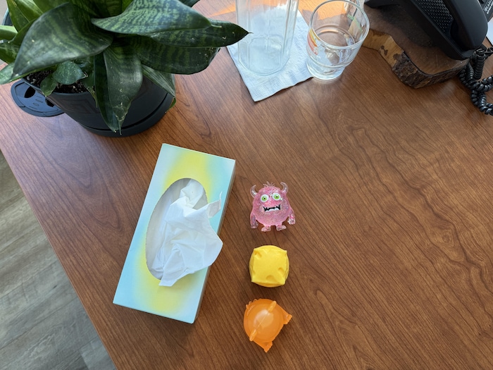 Une boîte de mouchoirs et des balles antistress sur un bureau.