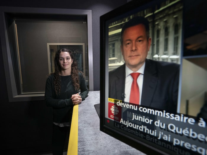 Une femme accoudée à un comptoir derrière un moniteur télé montrant l'animateur Sébastien Bovet et, en bas de l'écran, des sous-titres.