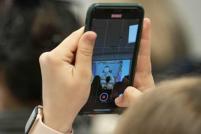 Une étudiante filme la téléconférence avec son téléphone.