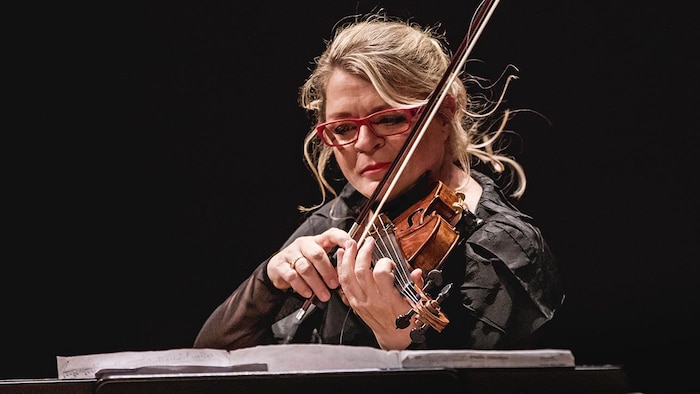 La violoniste en train de jouer de son instrument en regardant une partition