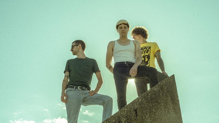 Les trois membres du groupe Population II regardent au loin.