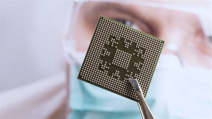 Un microchip sostenido en una pinza.