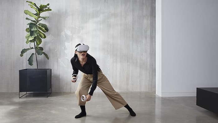 Une femme utilise un casque et des manettes de réalité virtuelle.
