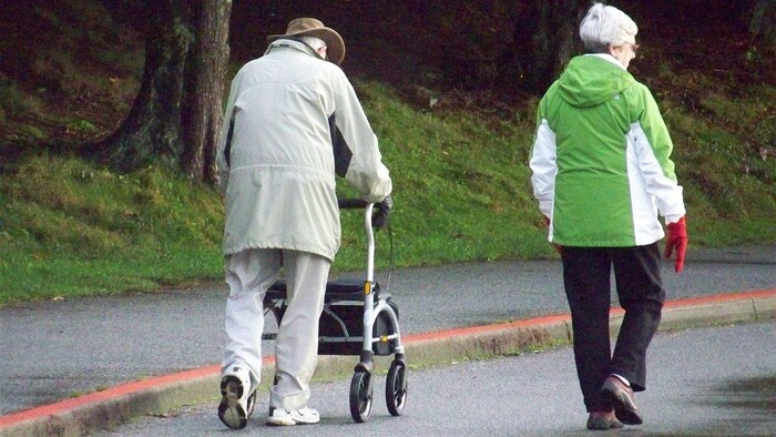 Deux aînés marchent sur une allée dans un parc.