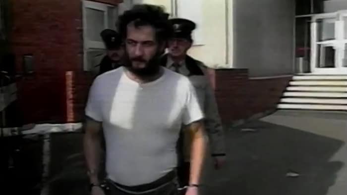 Allan Legere menotté et amené par deux policiers à son procès.