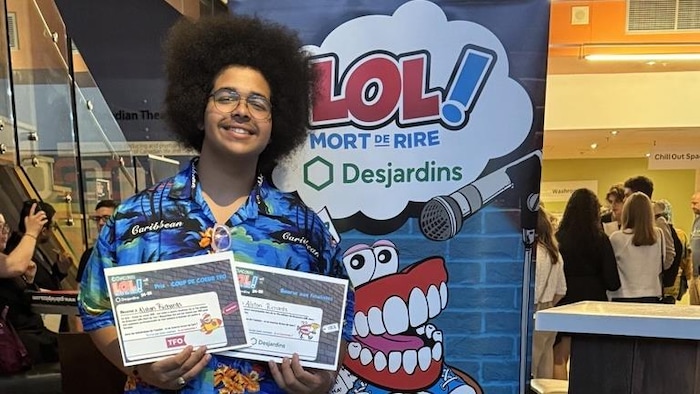 Alston Richard sourit devant une pancarte en tenant deux diplômes.