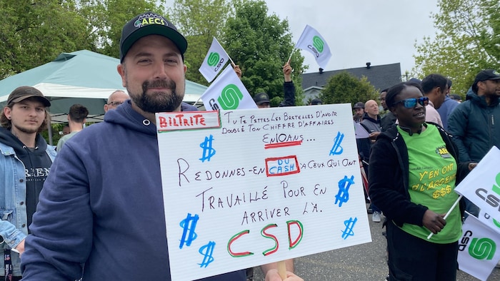 Un employé tient une pancarte.