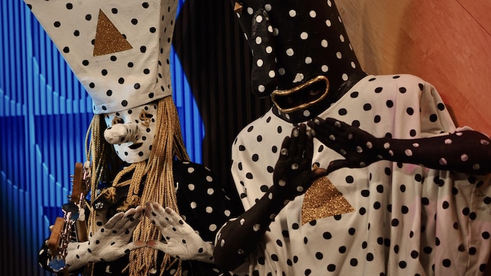 Les membres du groupe, revêtus de déguisements picotés, prennent la pose pour la photo en formant un triangle avec les mains.