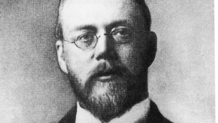 الفيزيائي والمخترع فيسندين، وهو رجل ذو شاربيْن ولحية ويرتدي نظارتيْن.