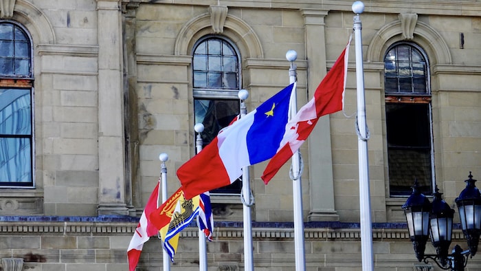 Les drapeaux du Canada, de l'Acadie et du Nouveau-Brunswick devant l'édifice de l'Assemblée législative du N.-B. à Fredericton.