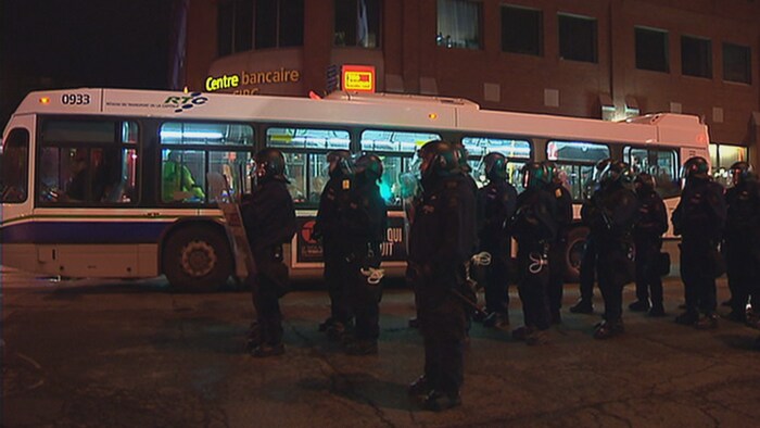 Des policiers du SPVQ montent la garde devant un autobus du RTC à l’intérieur duquel sont détenus des manifestants.