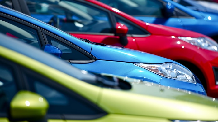 Des voitures neuves de différentes couleurs sont garées les unes à côté des autres.