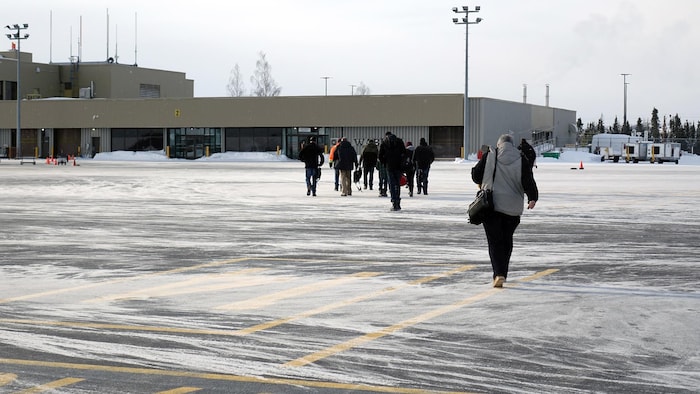 Des passager marchent à l'extérieur, entre l'avion et le terminal de Wabush.