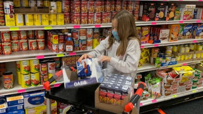 Jeune fille dans les allées de la banque alimentaire.