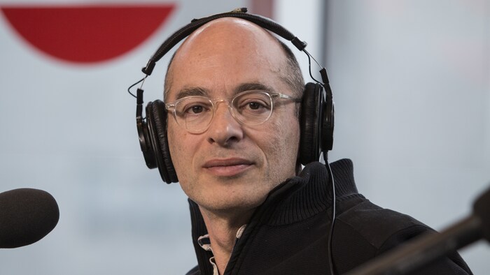 Bernard Werber, portant des écouteurs sur la tête, assis derrière un micro.