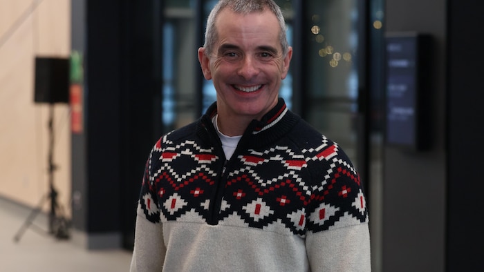 Bertrand Godin sourit dans l'atrium de Radio-Canada.