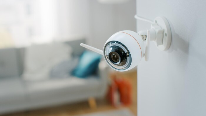 Gros plan d'une caméra de surveillance avec deux antennes installée sur le mur d'un appartement.