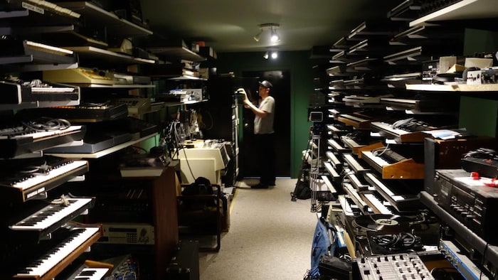 Une salle remplie d’instruments électroniques, un homme est debout dans le fond.
