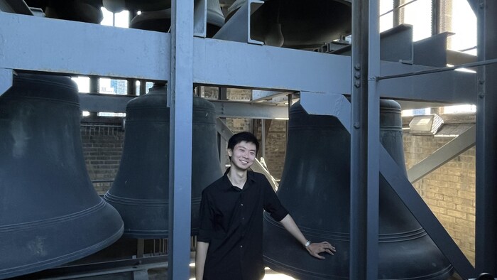 Joseph Min devant les cloches d'un carillon. 