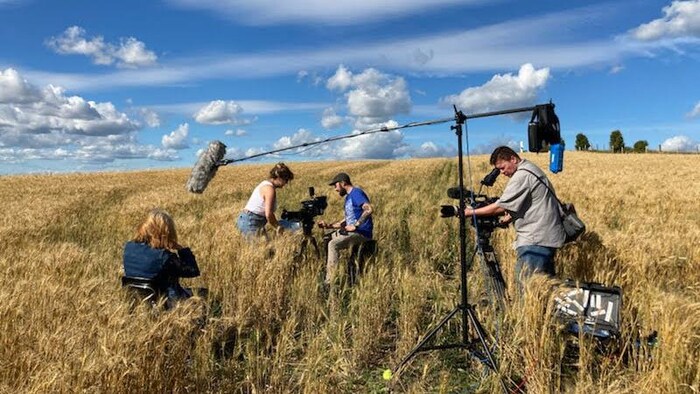 Une équipe de tournage est dans un champ.