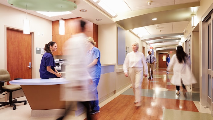 Des employés d'un hôpital circulent dans un corridor.