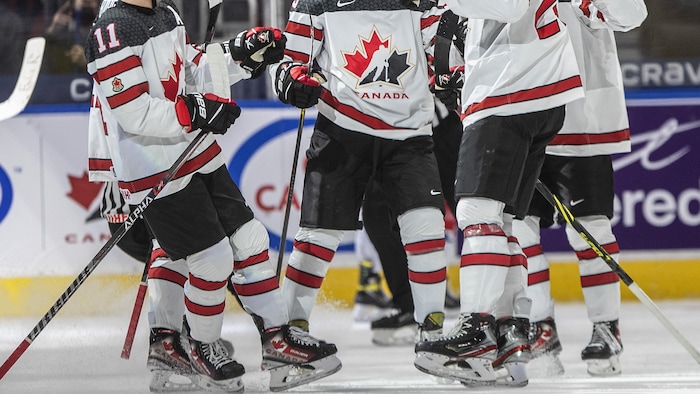 Los jugadores canadienses se reúnen en el hielo para celebrar. 