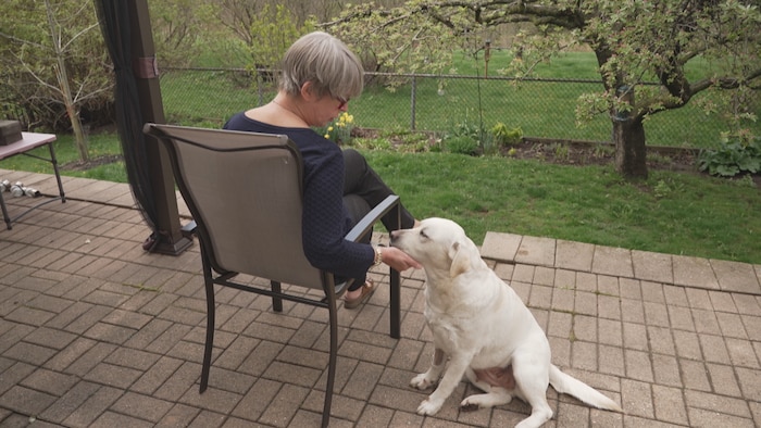Chantale Pinard est sur son patio avec son chien Ethel qu'elle caresse.