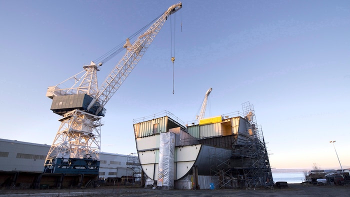 Une grue et une section de bateau en cale sèche dans le chantier naval.