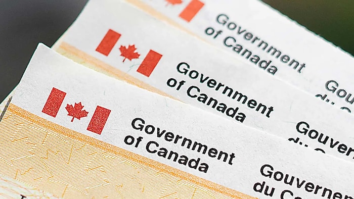 Trois chèques provenant du gouvernement du Canada, l'un par-dessus l'autre. 
