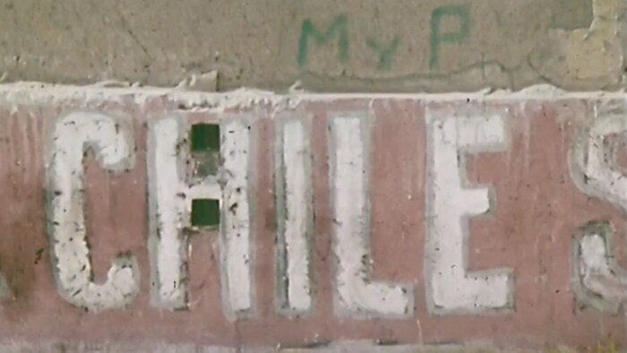 Partie d'une murale dans un quartier populaire de Santiago au Chili avec le nom du pays écrit en espagnol. 