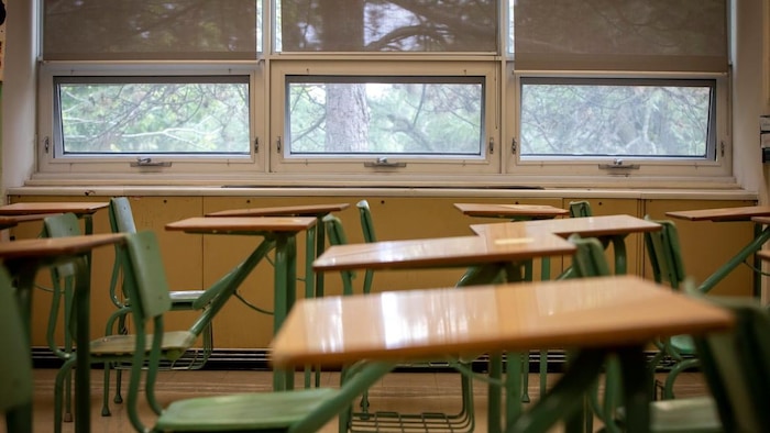 Une classe remplie de pupitres, sans élèves.