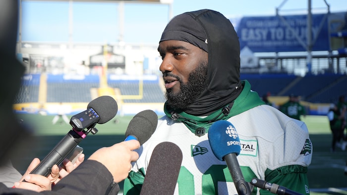 Un joueur de football avec un dossard devant des microphones.