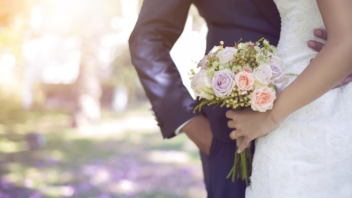 Un couple s'enlace, un bouquet de fleurs à la main.