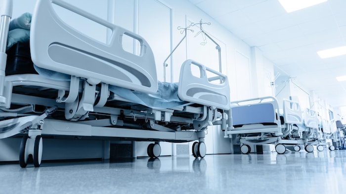 Des lits d'hôpital alignés dans un corridor.