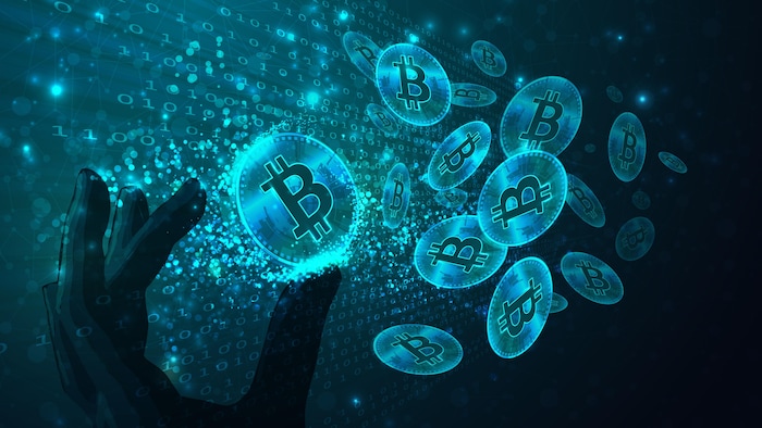 Une illustration avec des jetons bitcoins, du code binaire et une main.