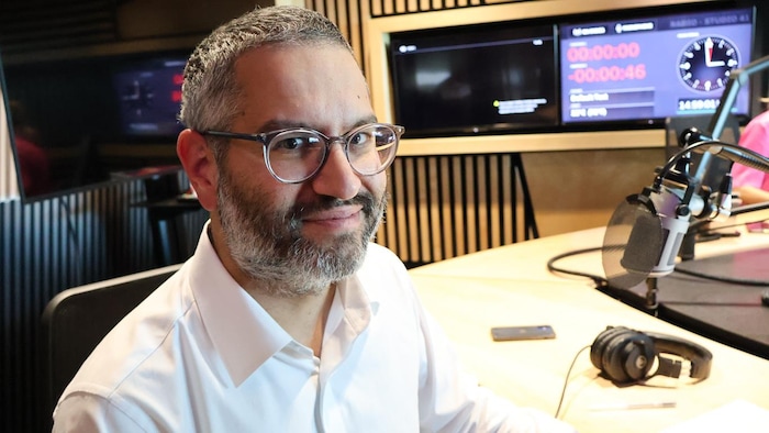 Alain Farah sourit à la array  d'un workplace  de radio.