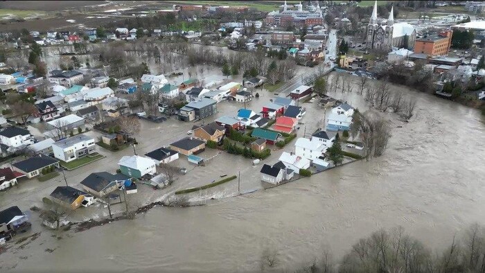 Des rues et des maisons sont inondées dans un centre-ville traversé par une rivière sinueuse. 