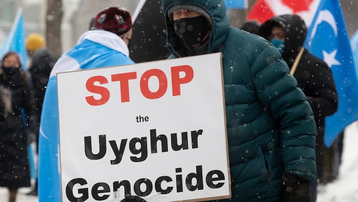 一名示威者舉著 "停止種族滅絕維吾爾人 "的牌子。