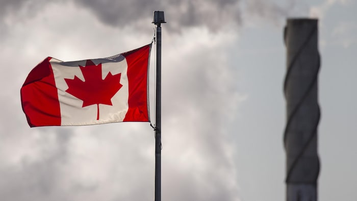 Una bandera canadiense con humo saliendo de una chimenea al fondo.