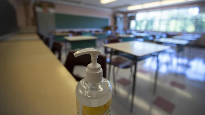 Une classe vide avec, en avant-plan, une bouteille de désinfectant.