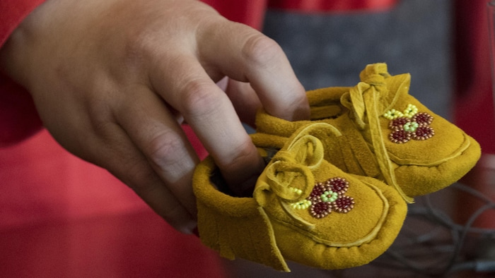 Gros plan sur une main qui tient une paire de mocassins.