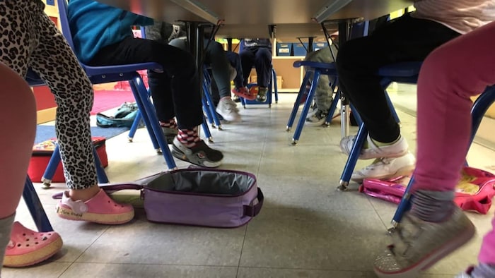 Jambes et pieds d'élèves vus sous une table