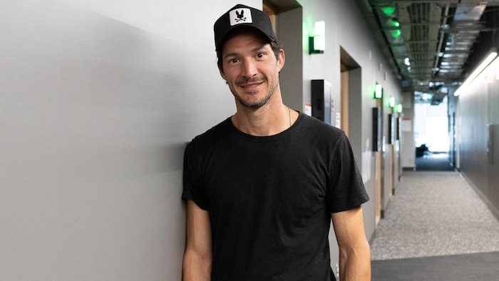 Un representation    d'Éric Bruneau, qui sourit et porte une casquette. Il airs  à l'intérieur.