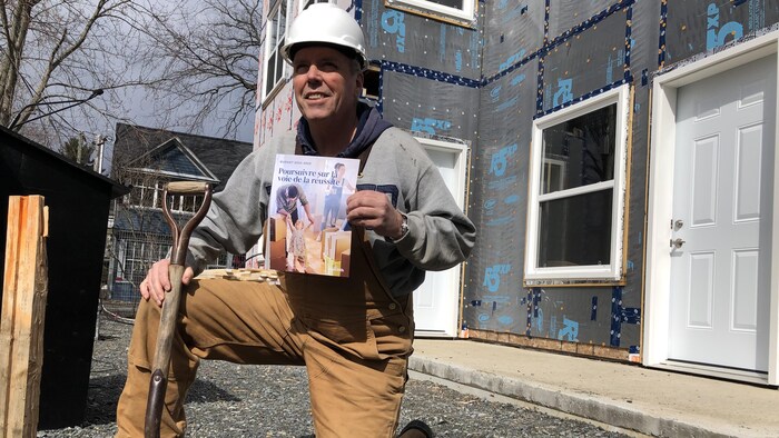 Ernie Steeves sur un genou, habillé en travailleur de la construction.