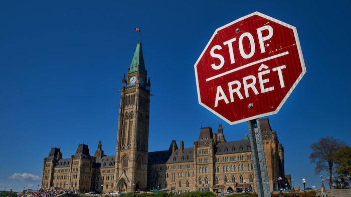Le parlement canadien, par beau temps à Ottawa. Un panneau d'arrêt bilingue se trouve devant.