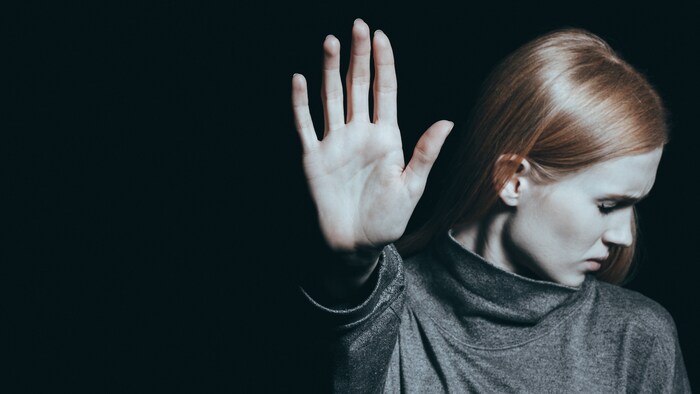 Une jeune femme met sa main devant elle pour signifier son refus.