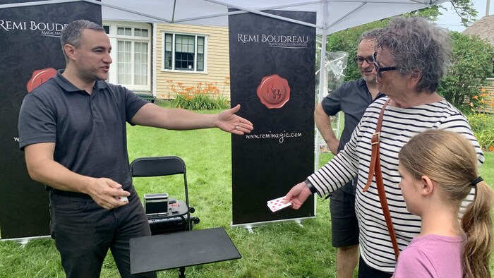 Un magicien présente des cartes à des gens dans le public.