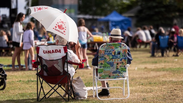 Couple de personnes âgées assises sur des chaises de camping «Canada» dans un parc.