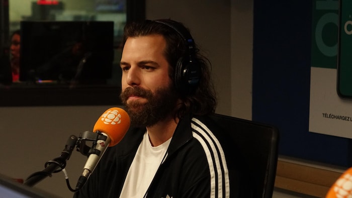 P-O Forget, assis devant un micro de Radio-Canada dans un studio de radio.