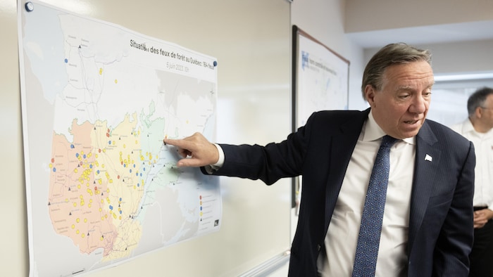 François Legault pointe un endroit sur une carte géographique du Québec.